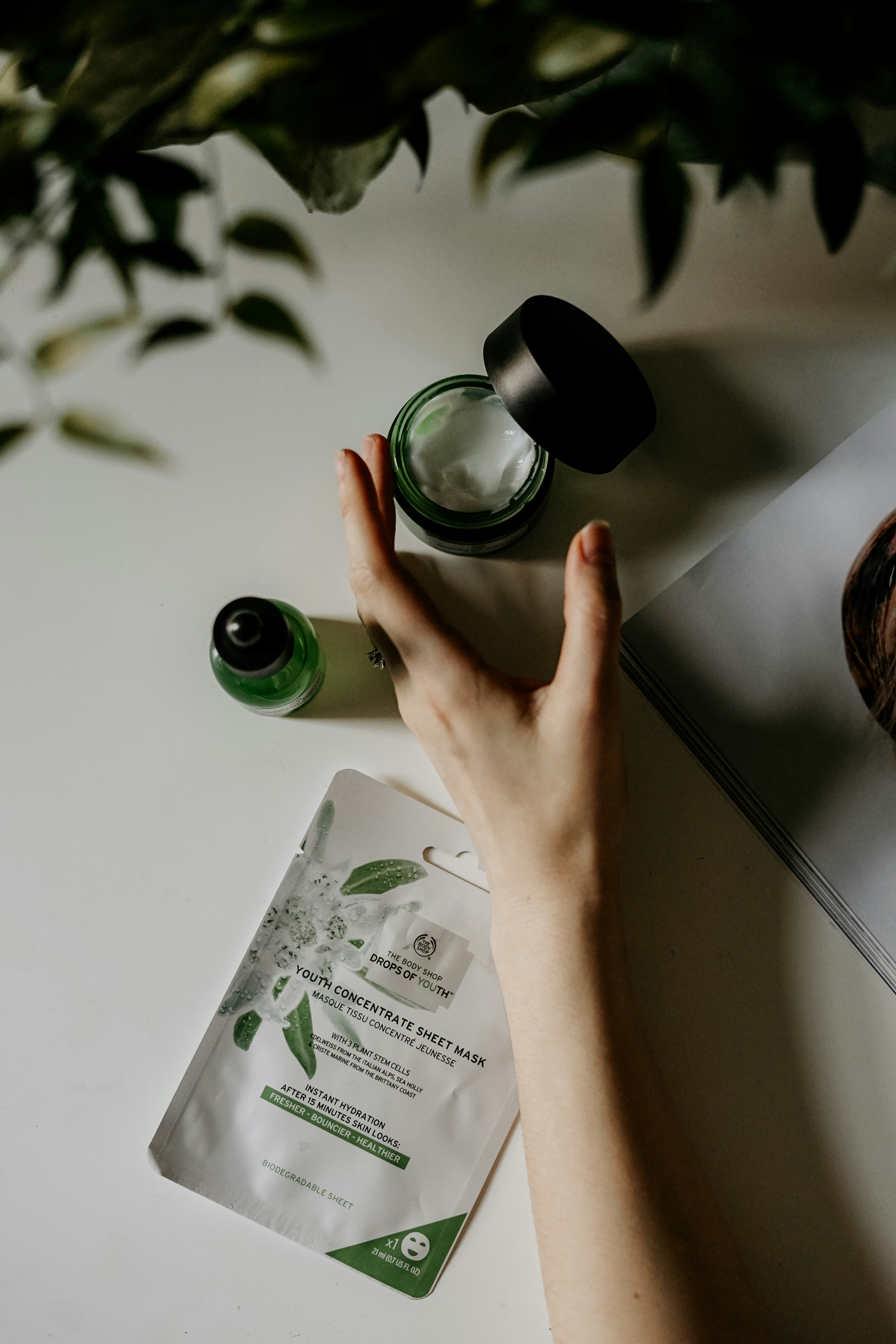 A woman reaches for a bottle of face cream.